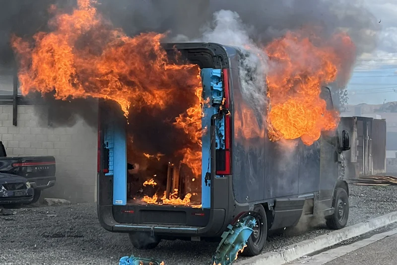Flames and smoke rising from a van with its rear doors open